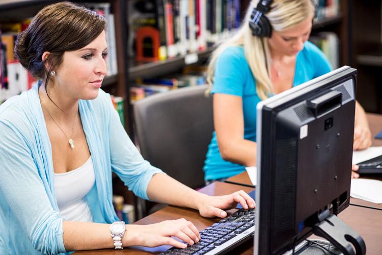 在图书馆用电脑工作的学生.